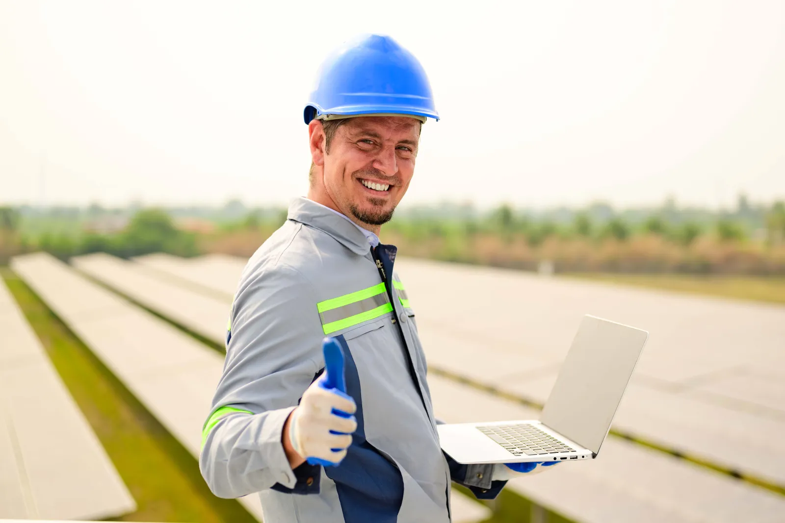 Een technieker met een laptop steekt zijn duim op voor zonnepanelen
